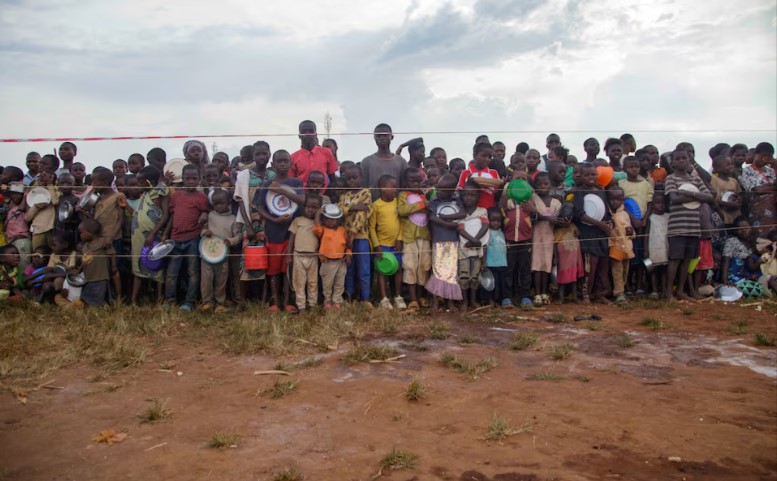 Jóvenes congoleños esperan detrás de una línea de cordón para recibir alimentos de socorro de voluntarios burundeses en el estadio de Rugombo Foto: Reuters
