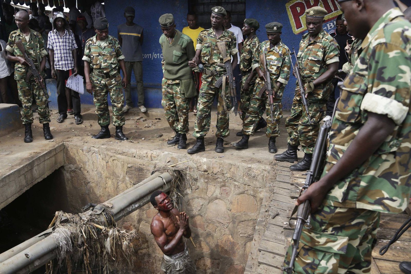 Un presunto miembro de la milicia juvenil del partido gobernante suplica a los soldados que lo protejan de una multitud