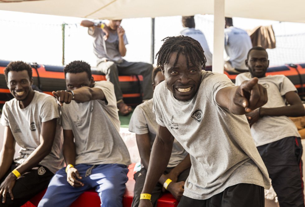 Inmigrantes a bordo del barco de ayuda Open Arms señalan los barcos que los acompañan mientras están acercándose al Puerto de Barcelona